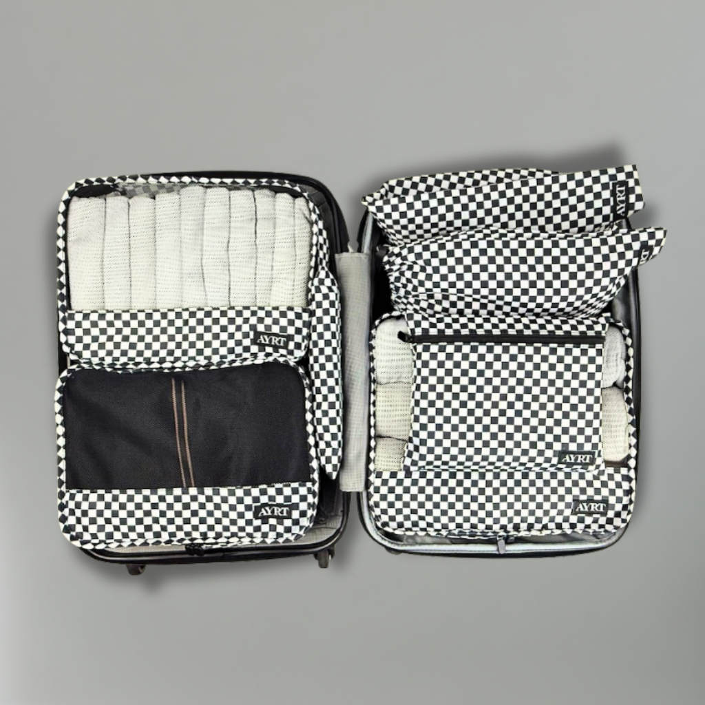 Open suitcase with checkered packing cubes on a gray background.